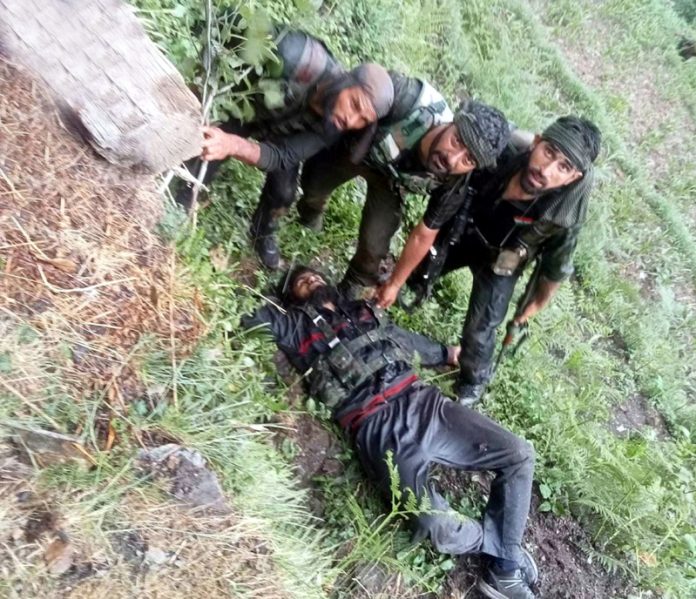 Army personnel pose with slain terrorist in Gandoh on Wednesday. -Excelsior/Tilak Raj