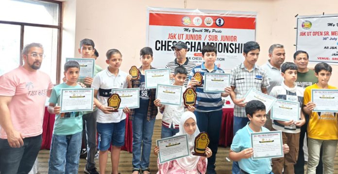 Chess players posing along with certificates.