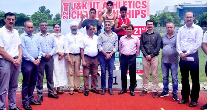 Athletes posing with medals on podium along with dignitaries during Athletics Championship.