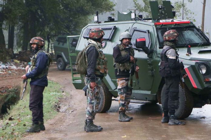 Security forces take position near the encounter site at Adigam Devsar village of Kulgam district on Saturday. -Excelsior/Sajjad Dar