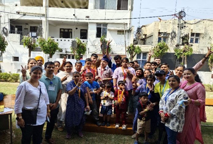 Children with special needs posing for group photograph along with teachers.