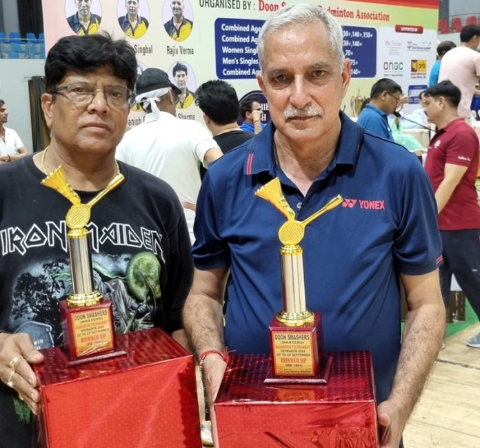 Romesh Sharma with his partner displaying trophies.