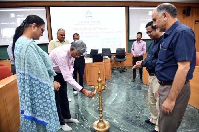 Chief guest lighting ceremonial lamp at inaugural of Capacity Building Program for Finance and Planning officials at IIM Jammu.